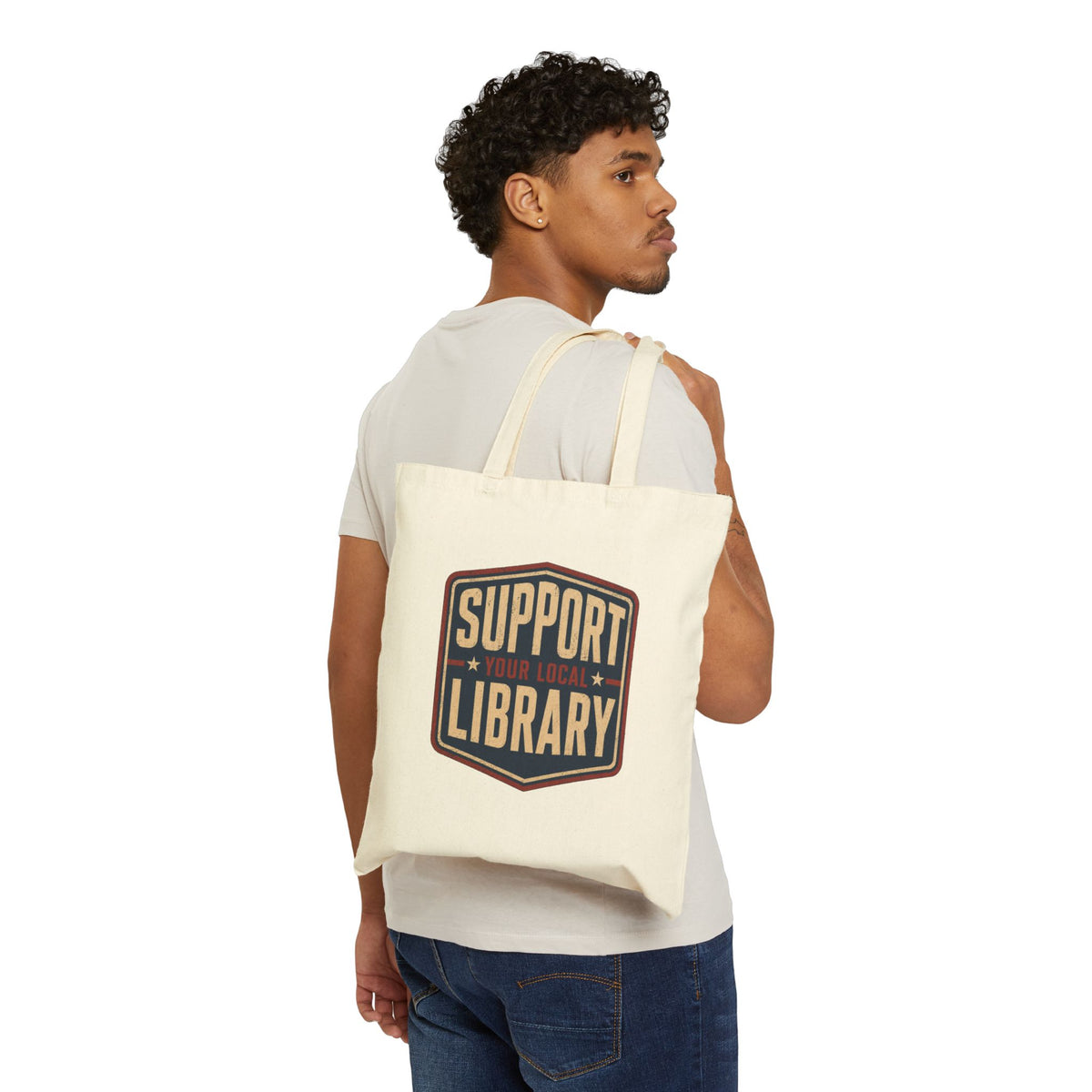 Man holding a beige tote with the saying Support Your Local Library