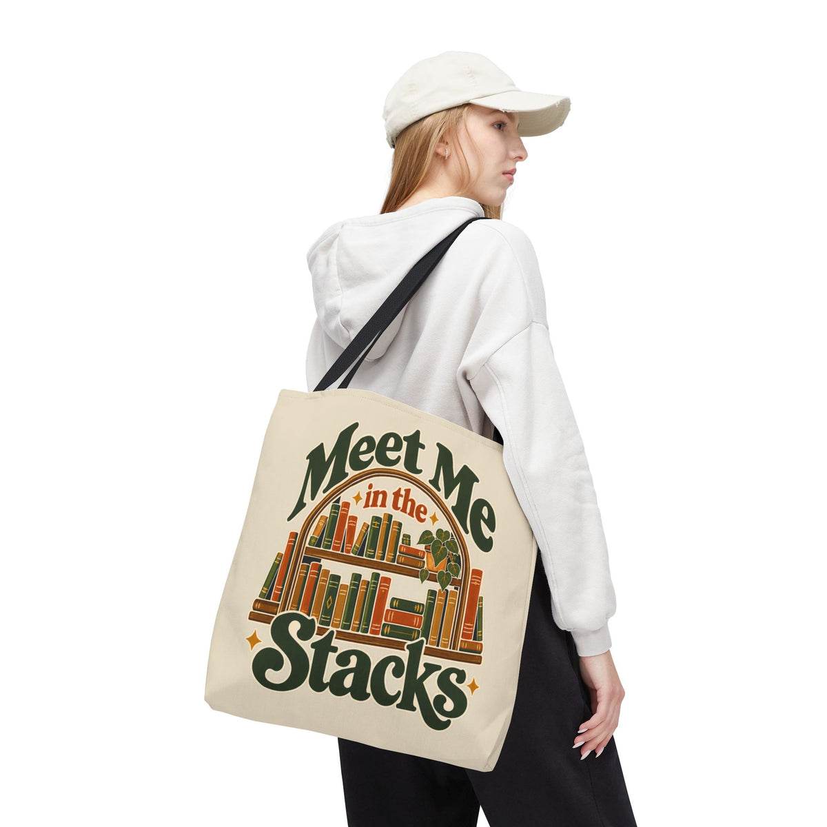 Person carrying Meet Me in the Stacks vintage booklover canvas tote bag over shoulder.