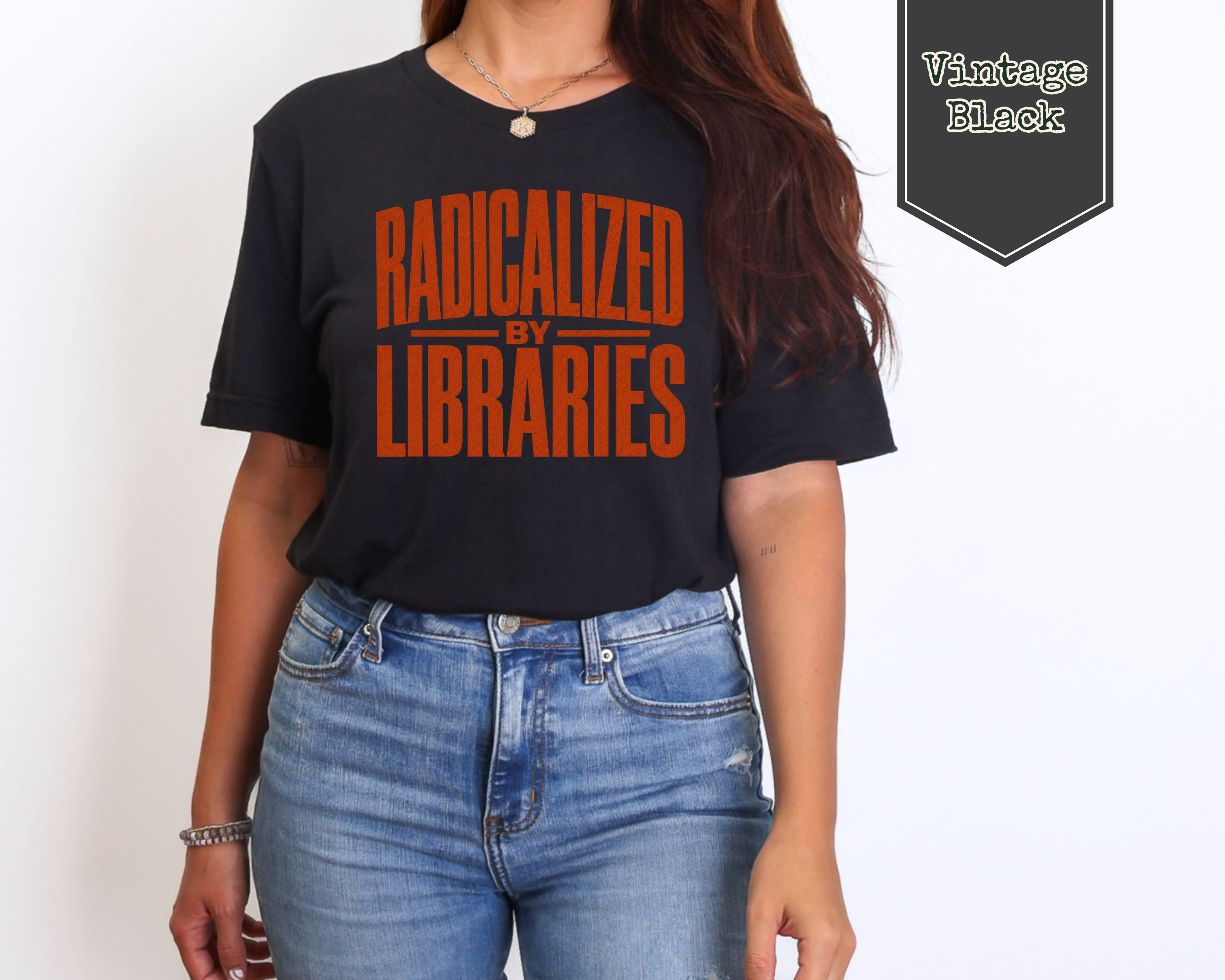 A woman wearing a vintage black graphic t-shirt with orange text that reads 'RADICALIZED BY LIBRARIES', paired with blue jeans. A badge in the top right corner reads 'Vintage Black'.