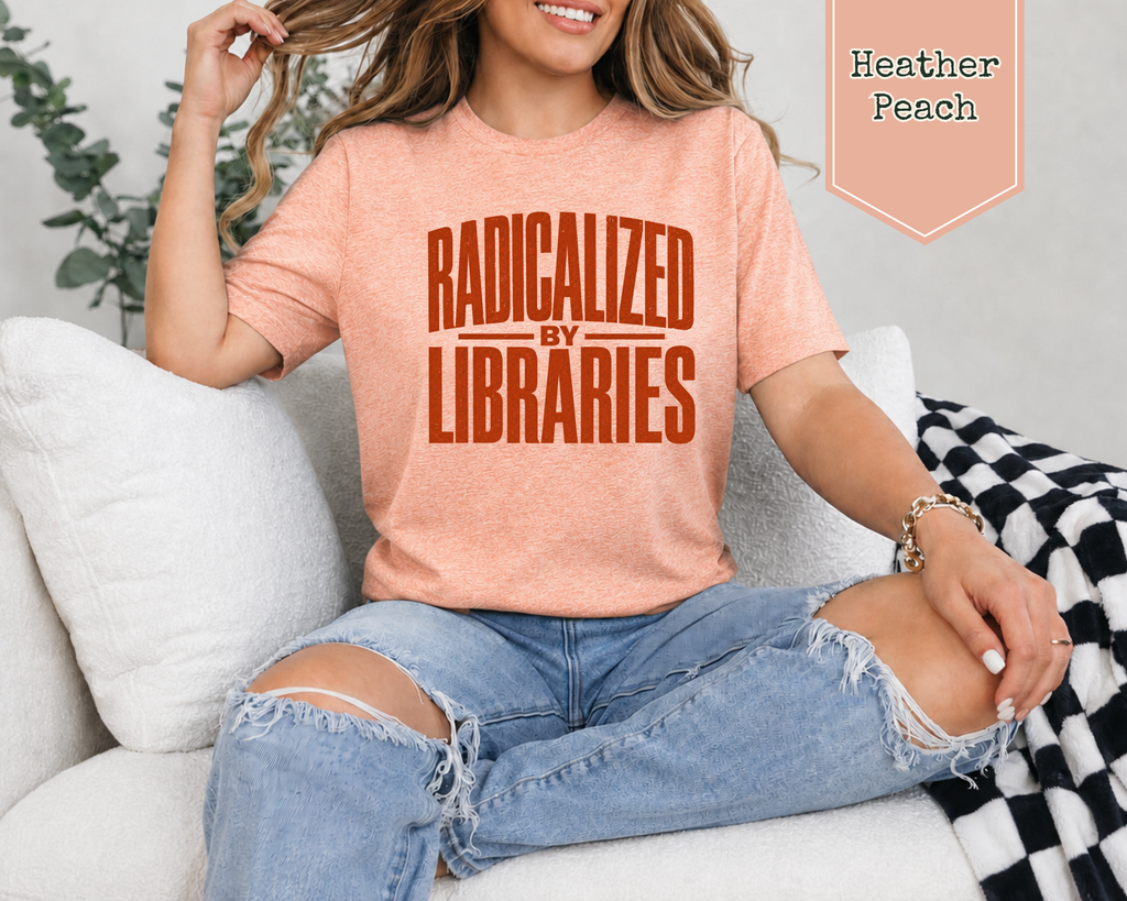A woman sitting on a white couch wearing a heather peach t-shirt with the text 'RADICALIZED BY LIBRARIES' in orange. She is wearing ripped blue jeans and a black and white checkered blanket is draped over the arm.