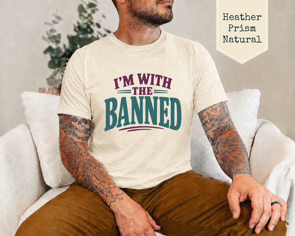 A man wearing a t-shirt sitting on a sofa. The t-shirt with purple and green phrase of I'm With The Banned.