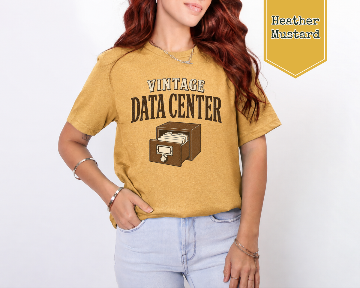 A woman standing wearing a heather mustard shirt. The tee shirt has a graphic on it that says Vintage Data Center with a vintage card catalog drawer.