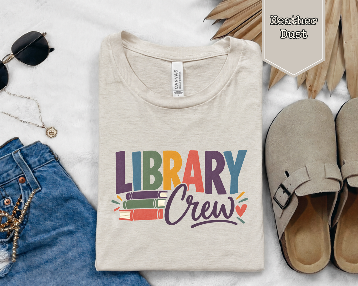 Folded Library Crew graphic tee styled in a flat lay with books, coffee mug, and everyday reading accessories.