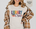 Heather Dust Library Crew t-shirt with colorful vintage stacked book illustration and retro typography on chest.