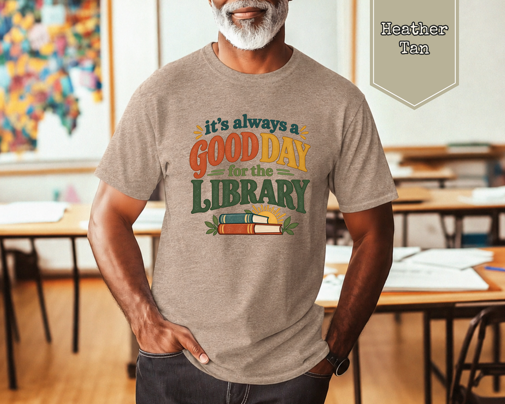 Man wearing Heather Stone Good Day for the Library book lover t-shirt sitting on couch.