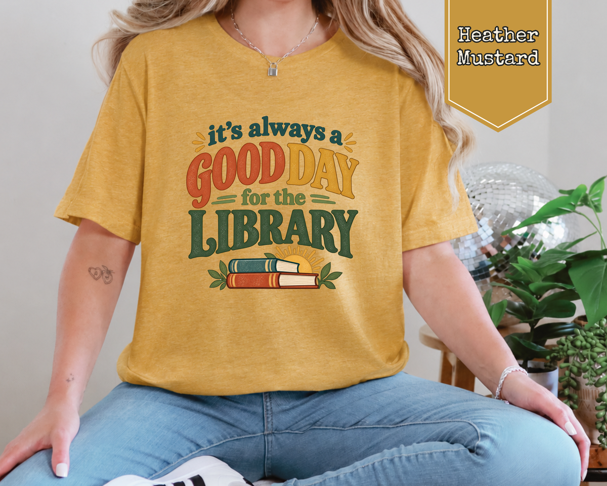 Woman wearing Sage green retro Good Day for the Library graphic t-shirt paired with jeans.