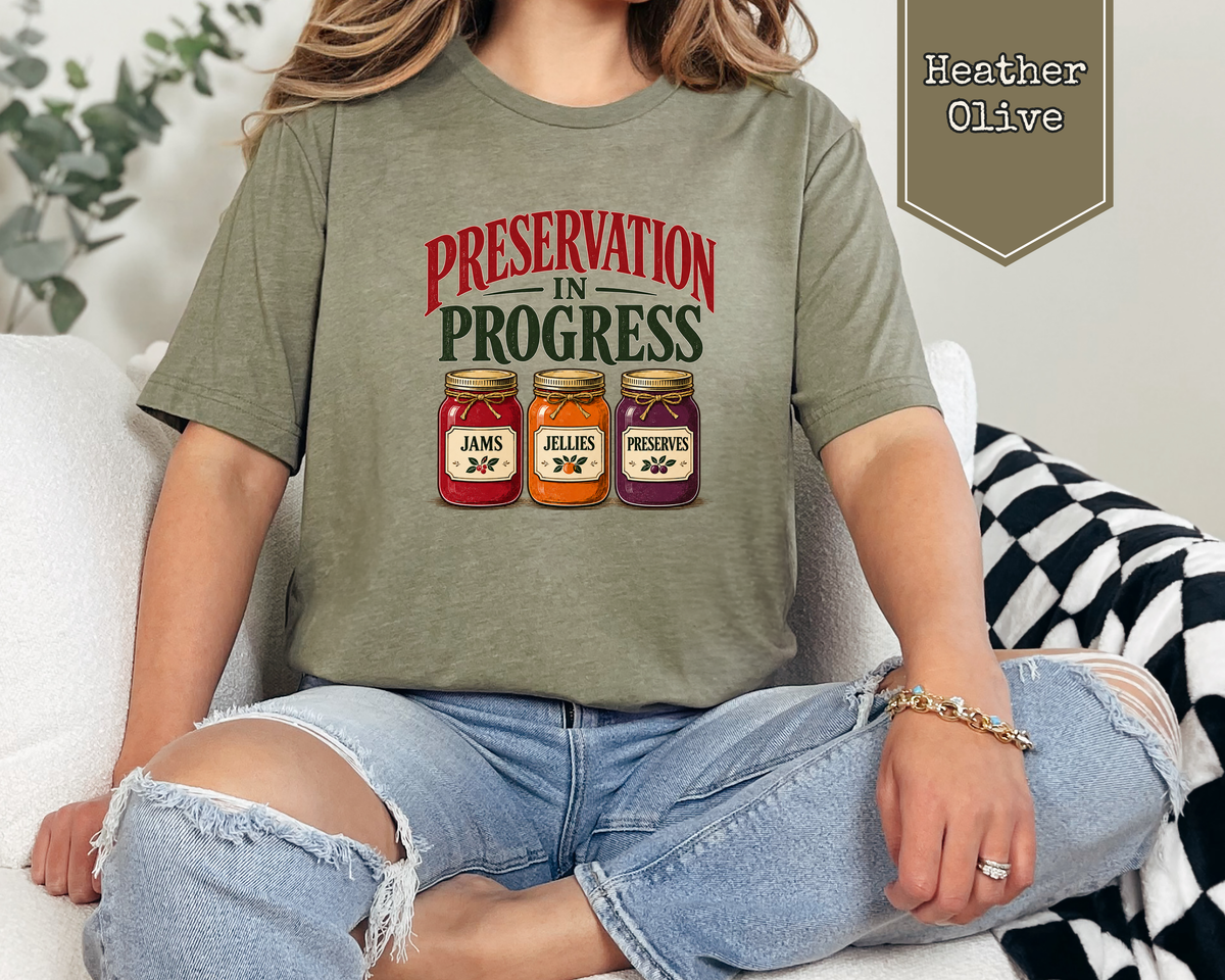 Person wearing Sage green Preservation in Progress t-shirt in library archives.