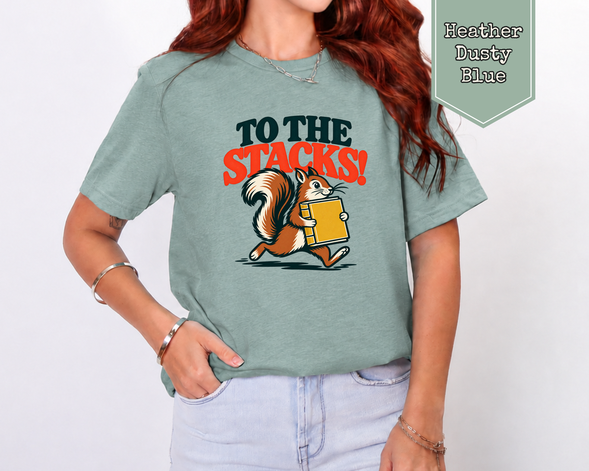 Man wearing Heather Mustard To The Stacks book lover graphic tee sitting on couch.