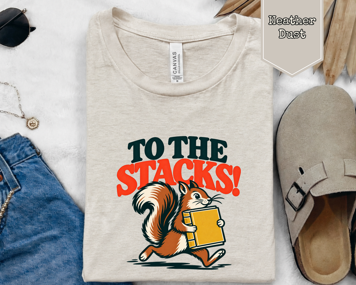 Folded To The Stacks squirrel librarian t-shirt styled in flat lay with books and coffee.