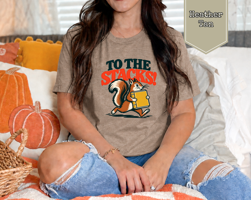 Woman wearing Sage green retro To The Stacks squirrel librarian t-shirt in reading room.
