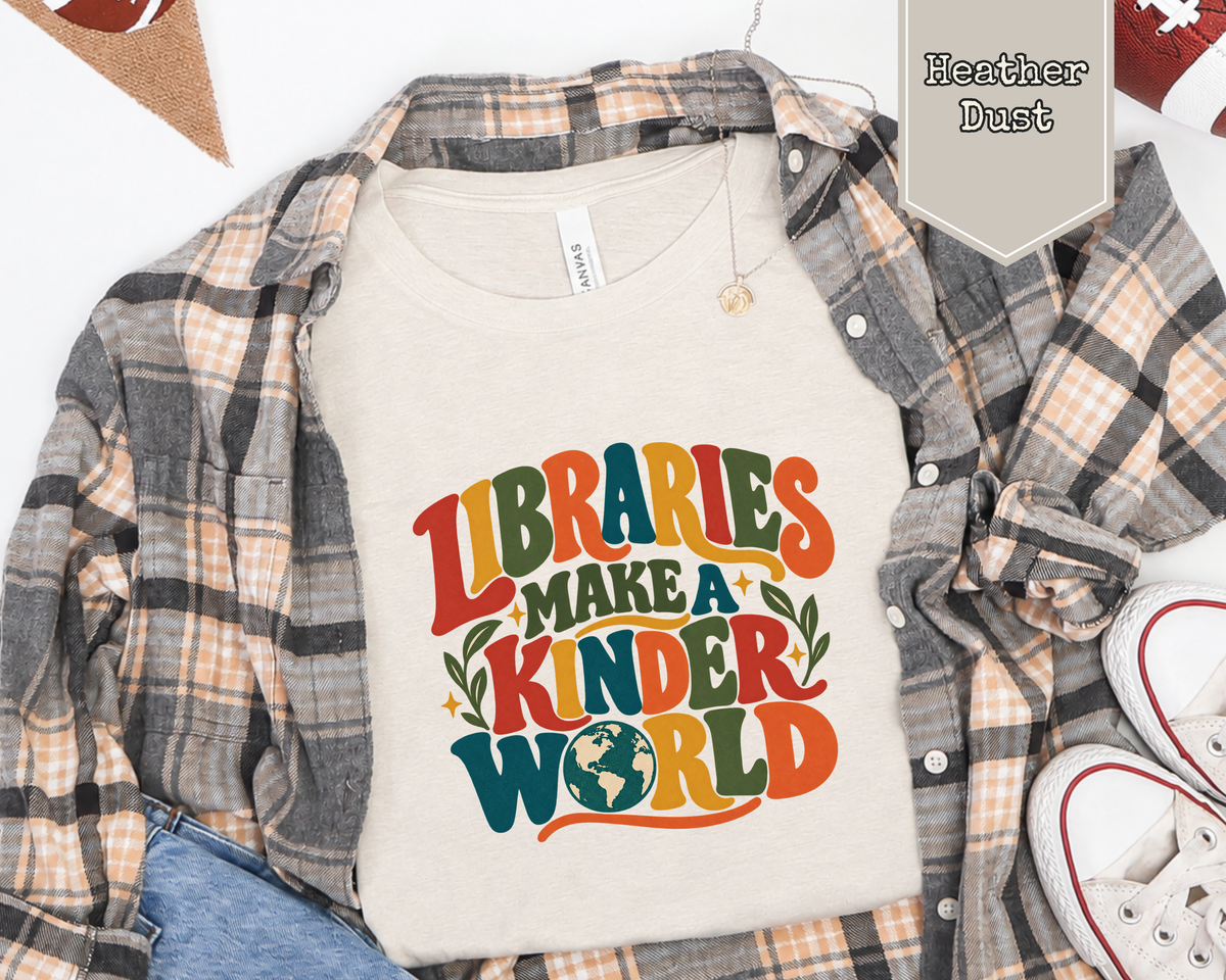 Folded Libraries Make a Kinder World graphic t-shirt styled in a flat lay with books, coffee mug, and library card accessories.