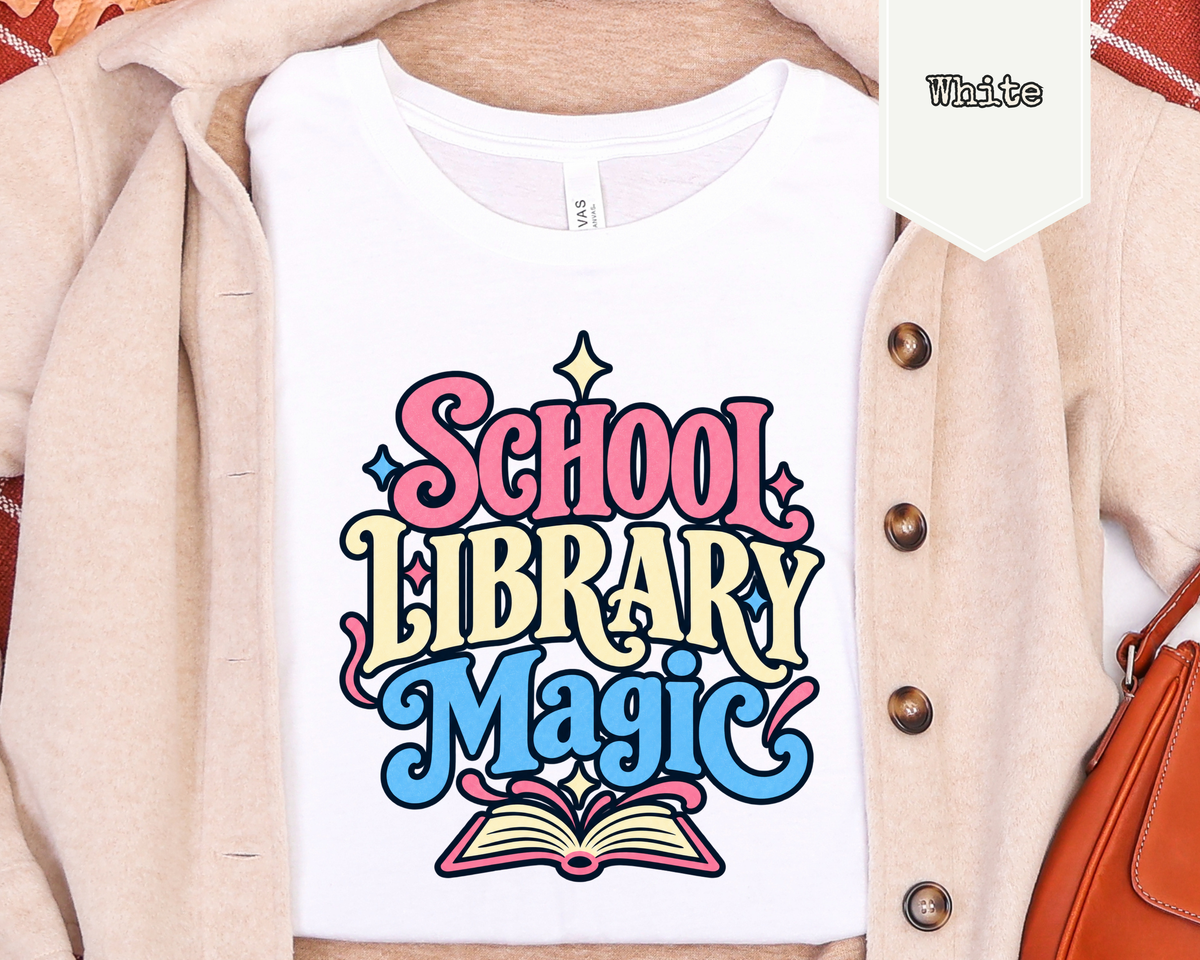 Folded School Library Magic graphic t-shirt styled in a flat lay with books, notepad, and school accessories.