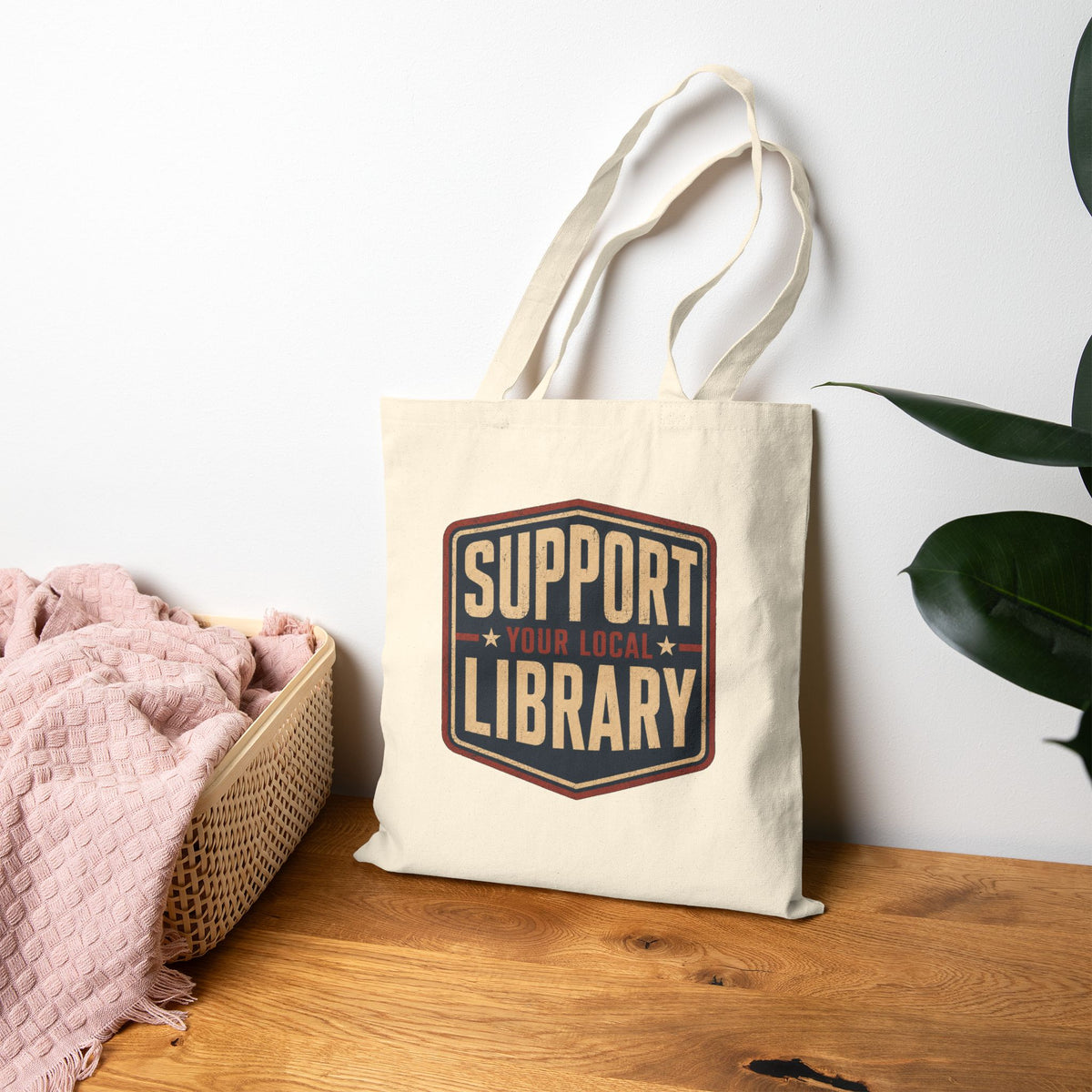 Support Your Local Libraries tote bag sitting against a wall on a bench